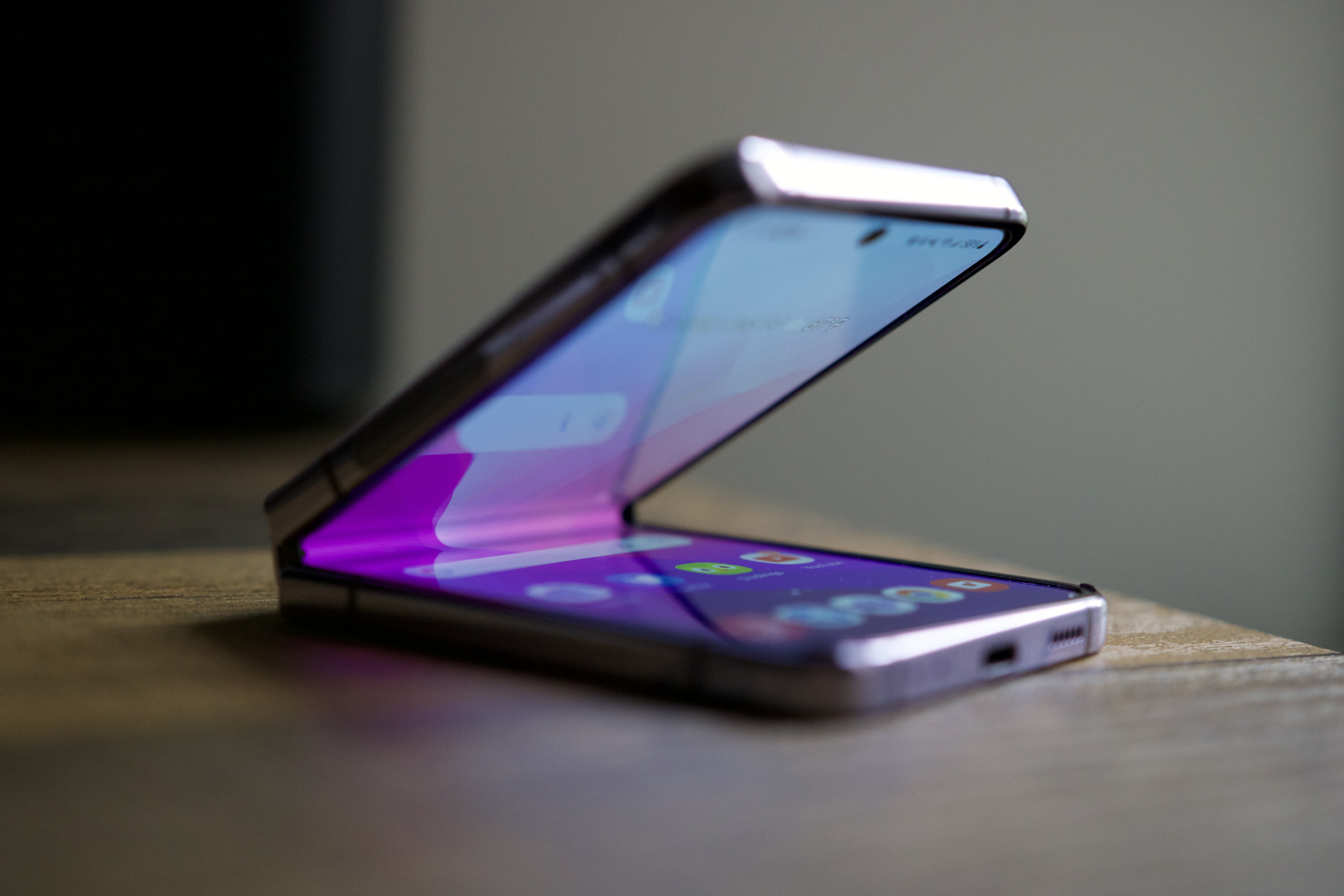 Samsung Galaxy Z Flip 4, setengah terbuka dan duduk di atas meja.